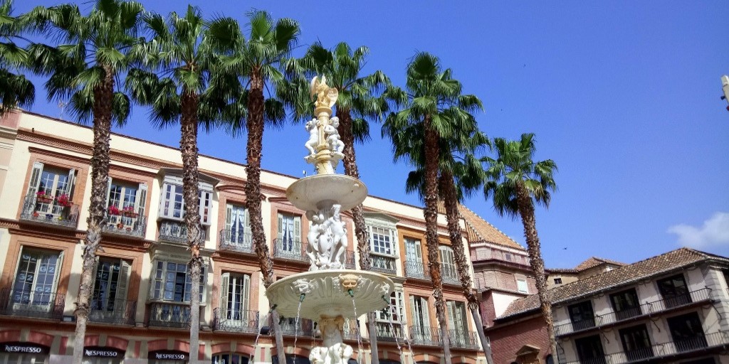 Close-up of fountain and palm trees on Plaza de la Constitución in Malaga